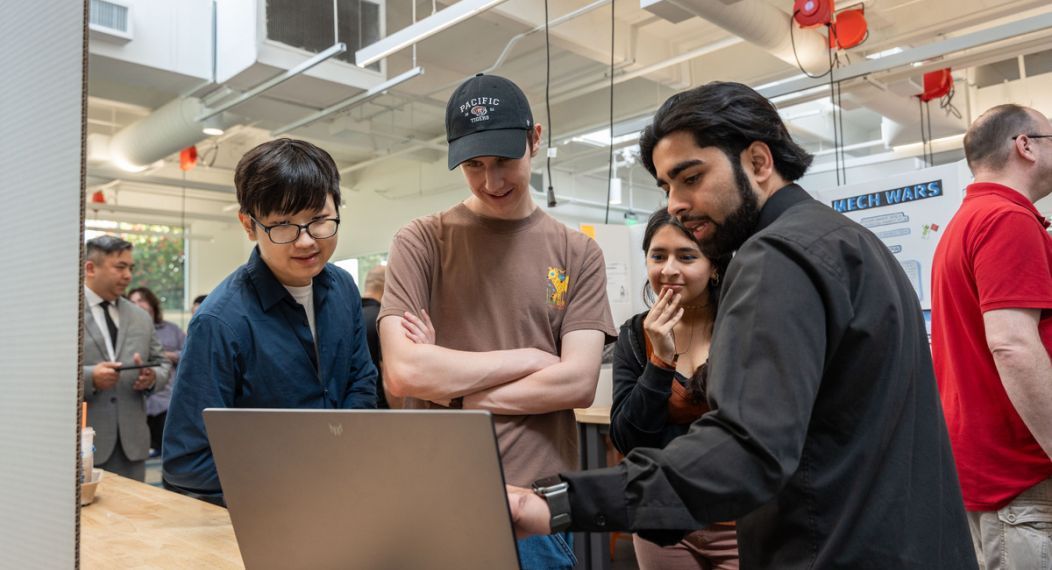 students look at a computer during senior project day